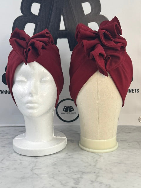 Both small and large mannequin heads wearing The Shondra Statement Wrap in Red Wine, showing the wrap fits a range of head sizes from approximately 21 to 25 inches in circumference